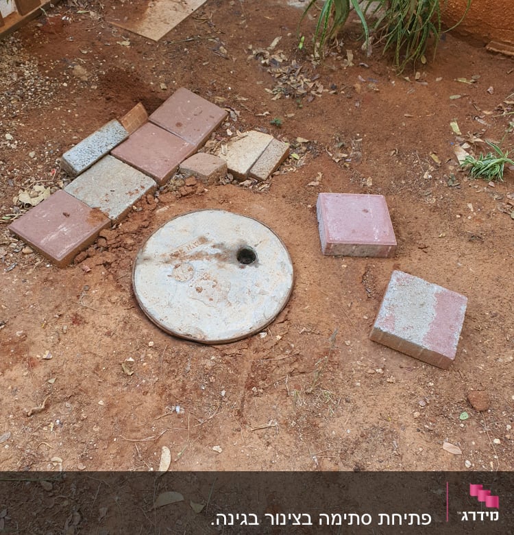 מכסה ביוב עגול על אדמה עם אריחים מסביב